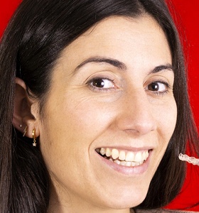 smiling woman against red background holding clear aligner