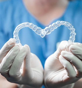 dental professional holding two clear aligners in heart shape