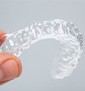 Hand holding clear aligner