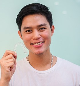Man smiling while holding Invisalign in Jacksonville