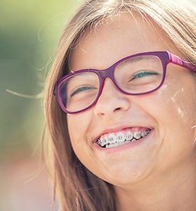 A young girl wearing glasses showing off her new braces in Jacksonville