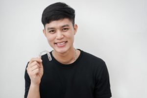 young man holding a clear aligner in Jacksonville 