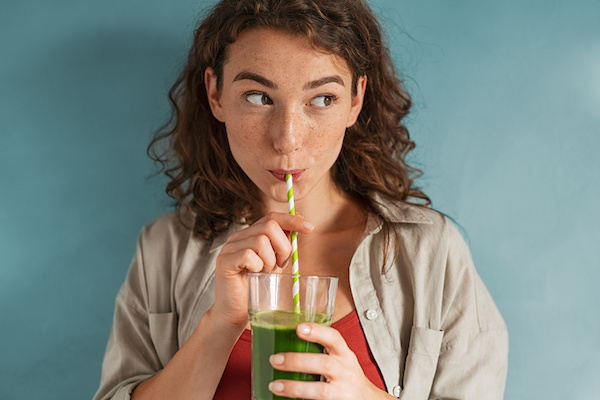 girl drinking smoothie in front of green background