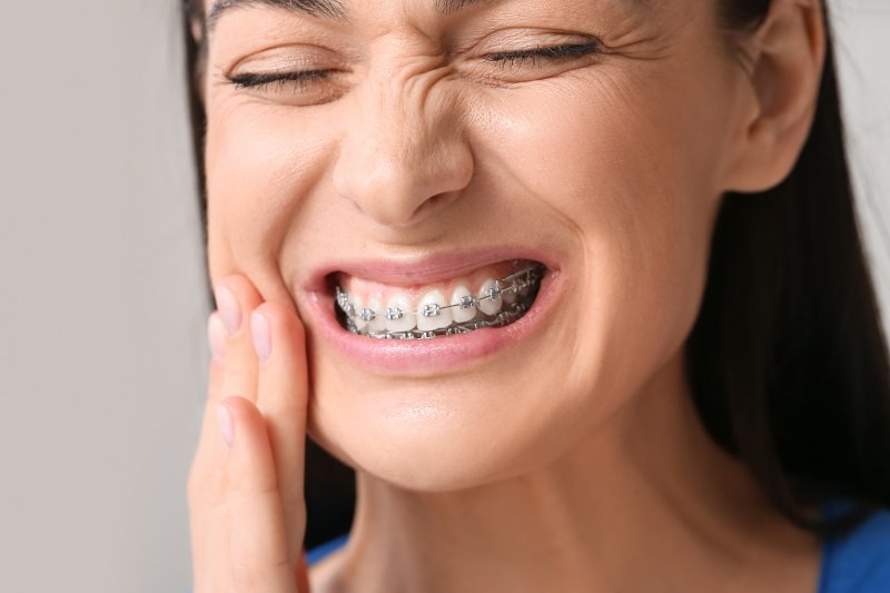 Patient with braces holding cheek due to mouth sore
